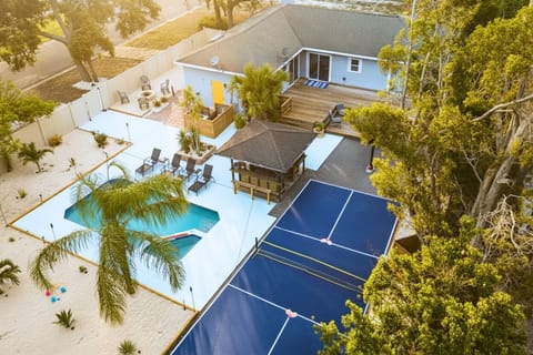 Aerial view of a sunny resort pool area with sunshades and palm trees.