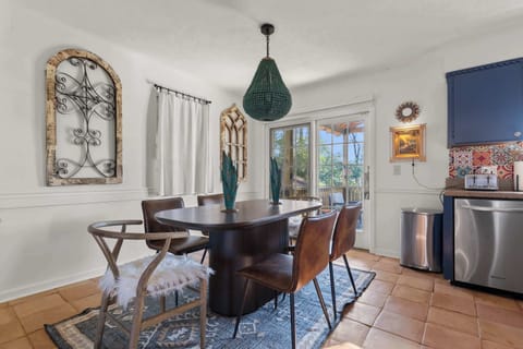Gather around the dark wood oval table under a statement beaded green pendant light in this thoughtfully curated dining space.