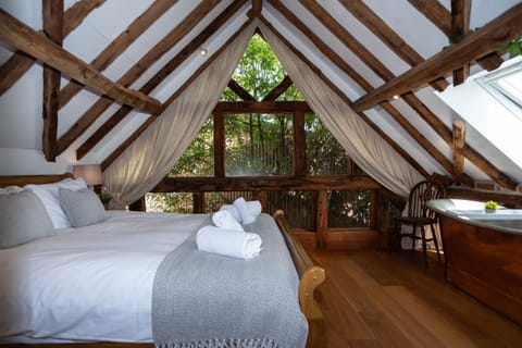 Master bedroom with luxurious treehouse vibes, large windows and a stunning copper bath — perfect for private, romantic escapes