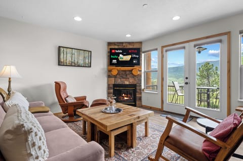 Gather in the inviting living room, where comfort meets views—Smart TV, fireplace, and doors to a mountain-view deck.