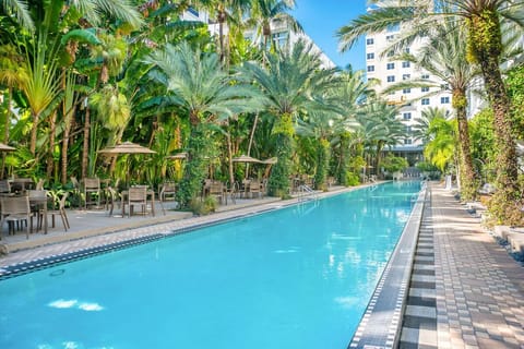 Swim leisurely laps beside breezy poolside tables and palms.