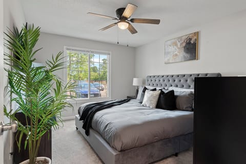 Relax in a cozy king bedroom with natural light, plush bedding, and style.