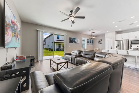 Spacious living room with leather seating, large TV, and patio access for relaxing evenings.