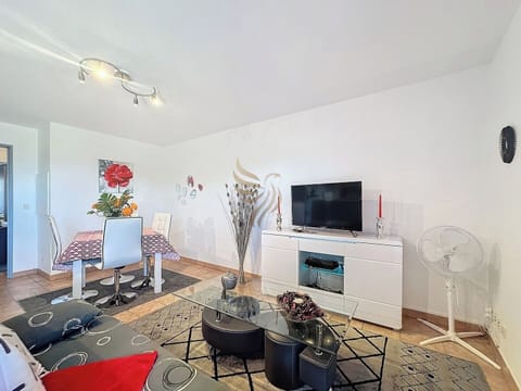 La table à manger sous un tableau floral crée une ambiance chaleureuse. Détendez-vous sur le canapé moderne en regardant la TV. L'espace encourage une atmosphère conviviale et reposante.