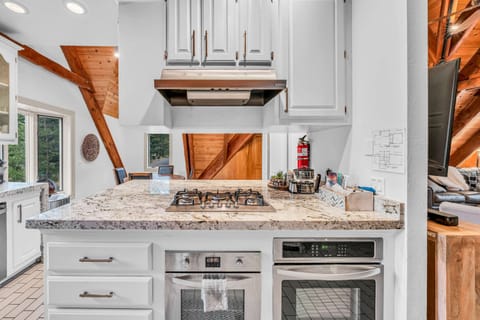 Kitchen: Stainless steel appliances, bar seating, tableware, cookware, gas range 