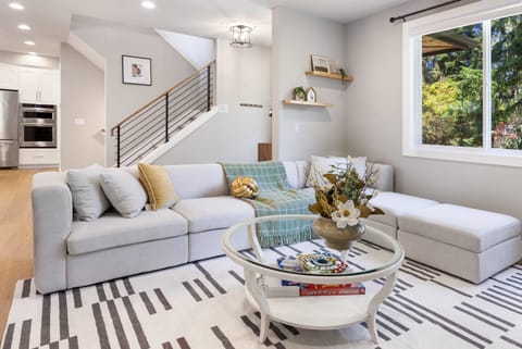 Soft sectional sofa adorned with textured throws and metallic accents. The transparent coffee table showcases board games
