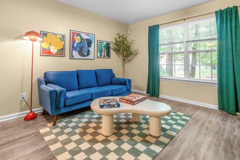 Living room with blue coach, bauahus decor, and windows with curtains