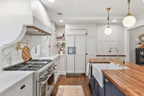 Recently updated state-of-the-art kitchen with a gas range, wall-mounted pot and kettle filler over the range, farm sink, and seating for four at the kitchen counter.