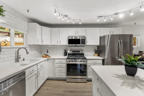 - Whip up your favorites in this fully equipped kitchen with sleek white cabinetry
- Stainless steel appliances and a gas stove make cooking easy and stylish
- Plenty of counter space, subway tile backsplash, and bright lighting complete the look