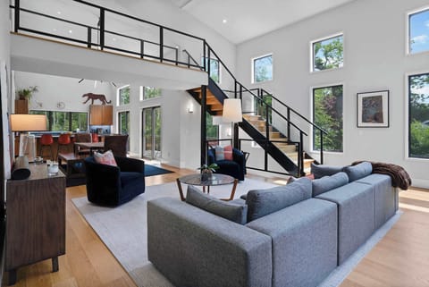 Double-height great room with steel staircase and walls of windows