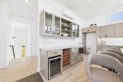 Wine fridge next to wine rack.  Under-counter pull out microwave.
