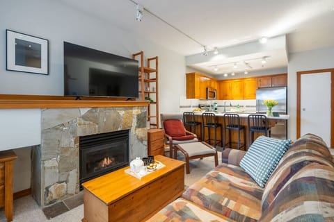 Open-concept living with gas fireplace, queen sofa bed, large TV & full kitchen.
