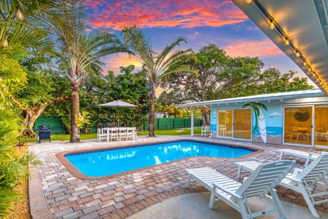 Unwind on the poolside loungers with the custom beach mural at your back and twilight skies overhead. Enjoy views of the outdoor dining area, yard games, and your private backyard retreat.