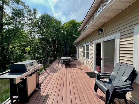Back patio with grill, patio chairs, and table overlooking woods & creek 
