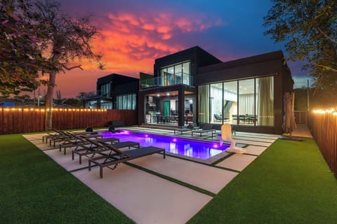 Modern home exterior with pool at sunset.