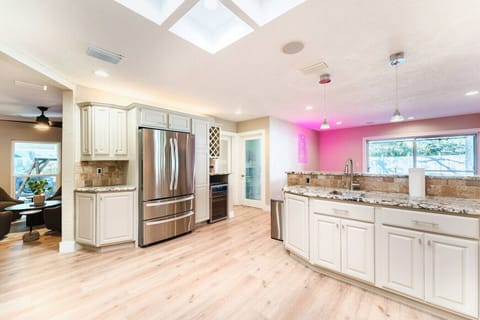 Enjoy cooking in this light-filled kitchen, featuring modern stainless steel appliances, elegant granite countertops, and a vibrant touch with the neon sign. A perfect blend of style and functionality for any home chef.