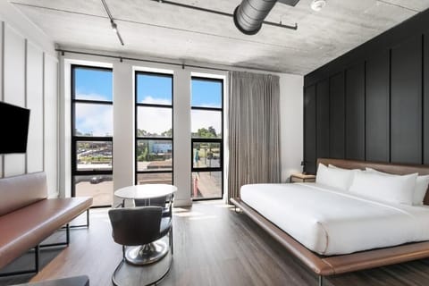 Wake refreshed in a sunlit bed beside dramatic city windows.