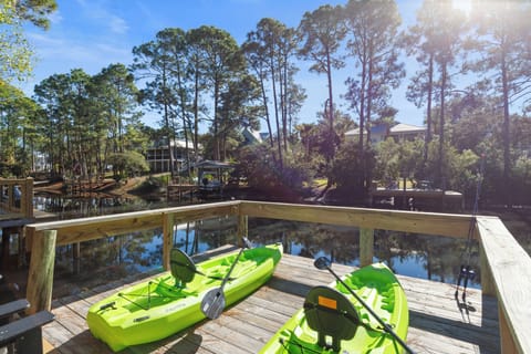 Bright green kayaks wait on the waterfront dock, ready for your peaceful paddle through tree-lined waterways.