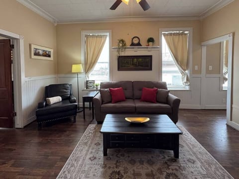 Comfortable living room with a dark sofa, armchair, and coffee table on a patterned rug.