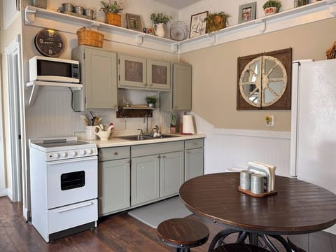 Charming kitchen with light green cabinets, a round wooden table, and rustic decor.