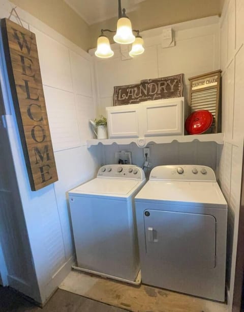 Laundry area featuring a washing machine and dryer, with a "Welcome" sign adding a homey touch.
