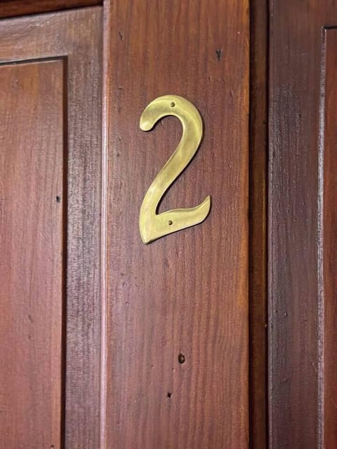 Close-up of a wooden door with a gold number "2".