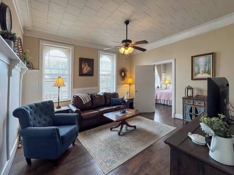 Living room with a blue armchair, a sofa, a coffee table, and a rug. There's a television and lamps