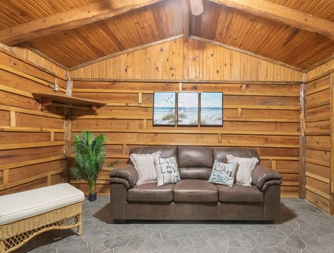 Cozy cabin living area with warm wooden walls and a comfortable leather sofa creating a relaxing atmosphere.
