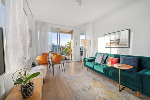 Unwind in a light-filled living area where floor-to-ceiling windows frame skyline views and open onto your private balcony—perfect for fresh air.