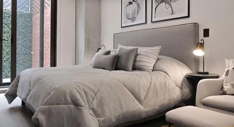 Soft, cozy bedroom w/ plush bed, warm lighting & calming neutral tones for a restful night