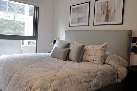 Cozy bedroom w/ plush bed, soft linens & a window bringing in gentle natural light