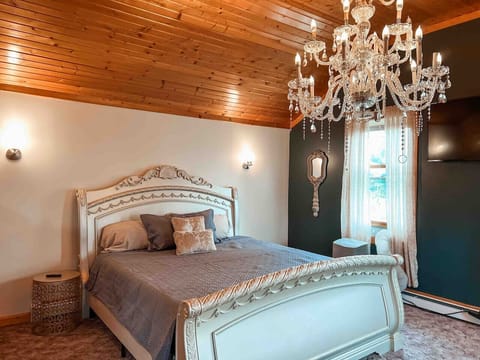 Sleep beneath a sparking chandelier in this elegant king bed, where warm wood ceilings meet luxurious finishes for a truly timeless retreat.