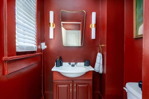 Bold red bathroom with sleek vanity and golden accents.