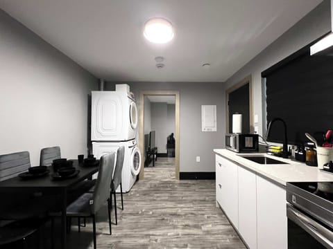 This photo shows the kitchen area, highlighting the convenience of a stacked washer and dryer unit located next to the dining table. The space includes a clean kitchen counter with a sink and provides a view into another room.
