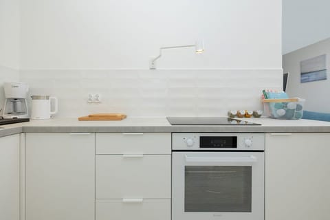A compact kitchen area featuring a white electric stove, built-in oven, and a clean white backsplash.