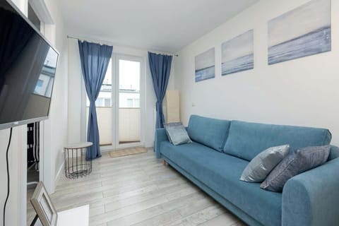 A bright living room featuring a blue corner sofa, modern decor, and large windows dressed with blue curtains.