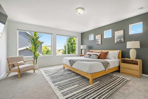 Bright and spacious bedroom with king-size bed, modern decor, and large windows offering natural light and scenic views. Cozy armchair and stylish accents create a relaxing retreat. Perfect for restful stays!