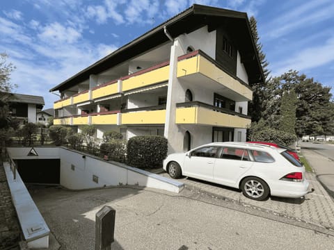 Exterior view of the house with underground garage access and guest parking spaces.