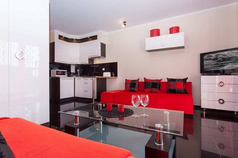A small dining setup next to the kitchenette, featuring sleek white cabinets and black countertops for a clean, minimalist look.