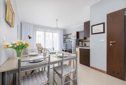 An open-plan dining area with a table set for six, adjacent to a modern kitchen with wooden and dark cabinetry. Ideal for hosting meals and social gatherings.