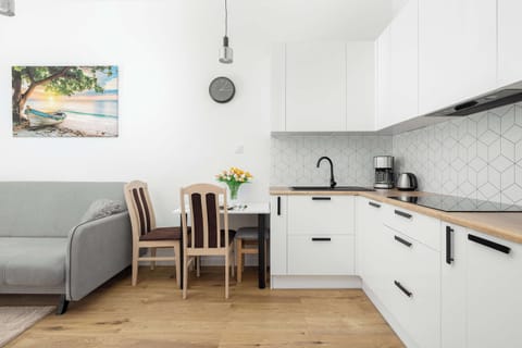 A modern kitchen with sleek white cabinetry, black appliances, and wooden countertops.

