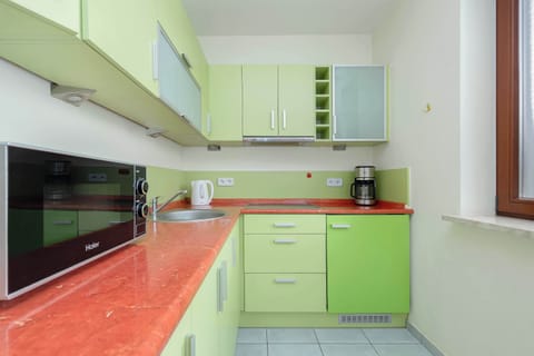 Kitchenette with electric cooktop, oven, electric kettle, coffee maker, toaster, refrigerator with freezer and washing machine.