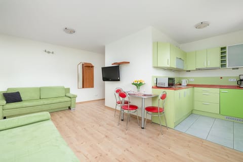 Living room with comfortable sofas, TV and kitchenette with dining area.