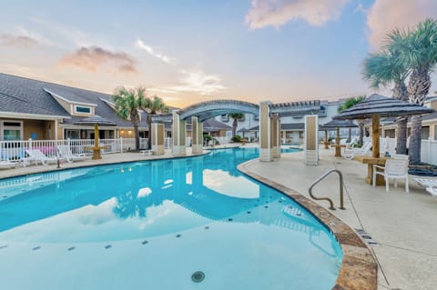 Beautiful resort-style pool area with tropical palms and covered seating pavilions, perfect for relaxing during golden hour.