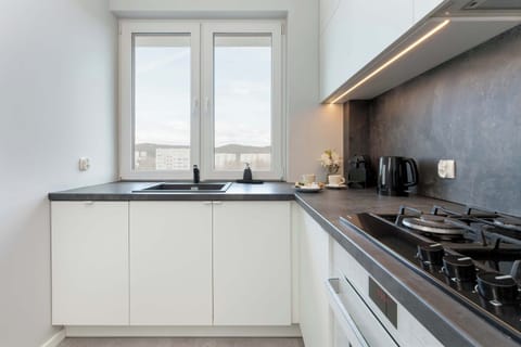 A sleek, fully equipped kitchen with white cabinetry, ample countertop space, and high-quality built-in appliances.