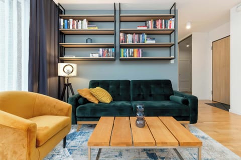 Living room with green sofa and bookshelf – A stylish lounge area with a cozy green sofa, designer armchair, and a built-in bookcase.