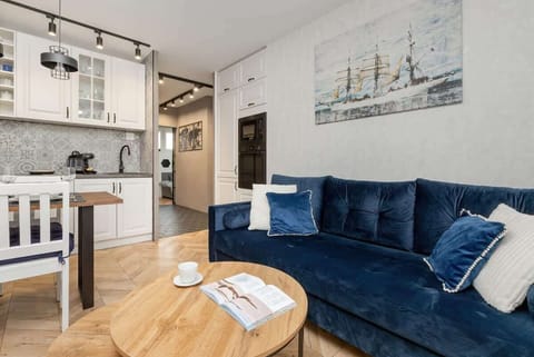 A living-dining combination space with a blue sofa and wooden table. The parquet flooring adds warmth to the overall design.