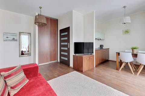  A cozy living room with a sofa, a TV, and a simple coffee table, paired with light-colored walls and warm natural light, providing a comfortable and relaxing space.