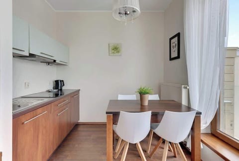A sleek kitchen with a wooden dining table, contemporary chairs, and a well-organized layout, offering a warm and inviting cooking space with natural light coming in from the windows.