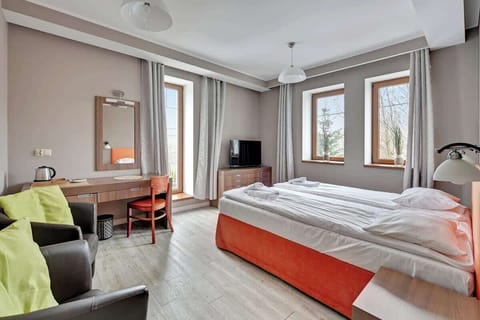A simple bedroom featuring a bed, a TV unit, and a calm, neutral decor scheme, designed for relaxation.